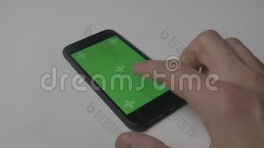 使用智能手机触摸的特写镜头，白色<strong>桌面背景</strong>上有绿色屏幕彩色键